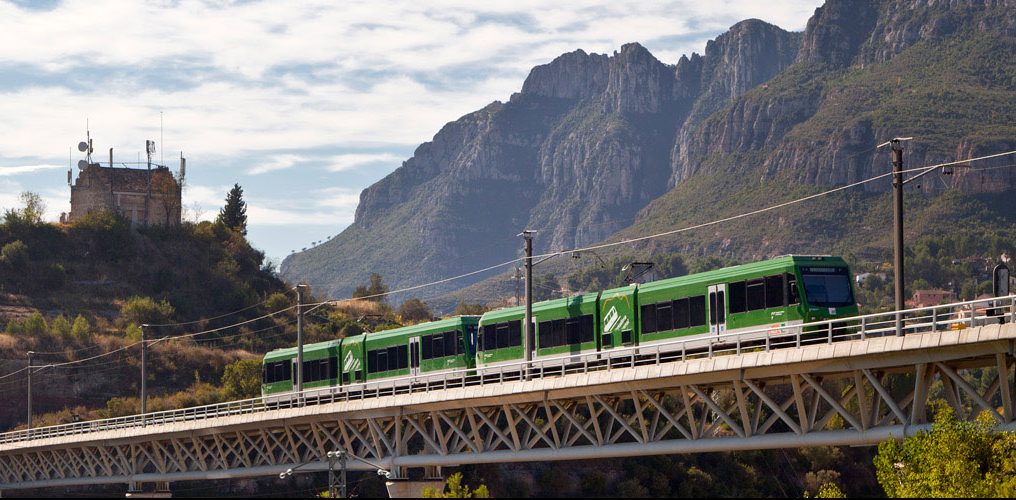El tren de Montserrat pasando sobre un puente metálico con la sierra de fondo