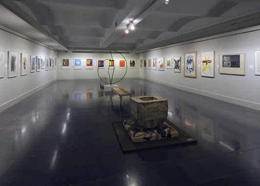 Una sala de exposición con pinturas y una escultura en el centro de la habitación