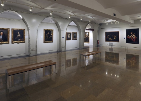 Una sala de exposición de pinturas con bancos